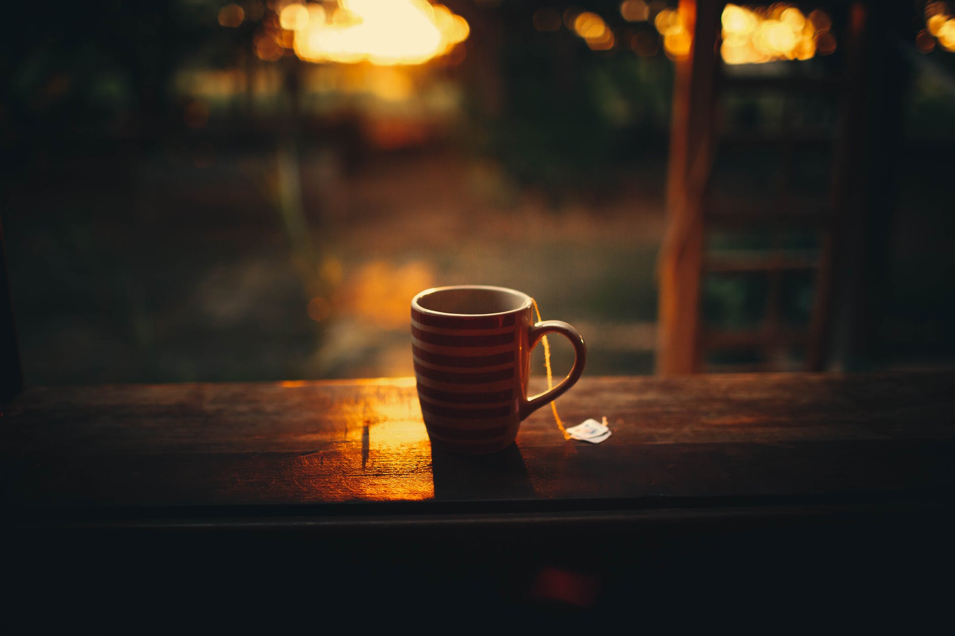 mug with teabag placed on wooden railing of forest house balcony